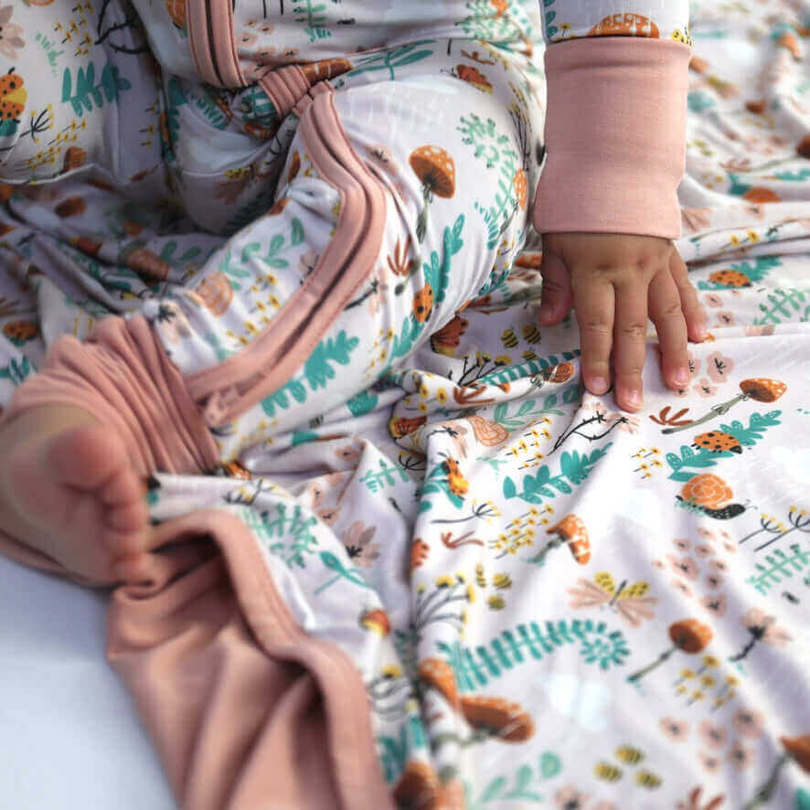 Close-up of a baby's hand on soft bamboo clothing with colorful floral patterns.