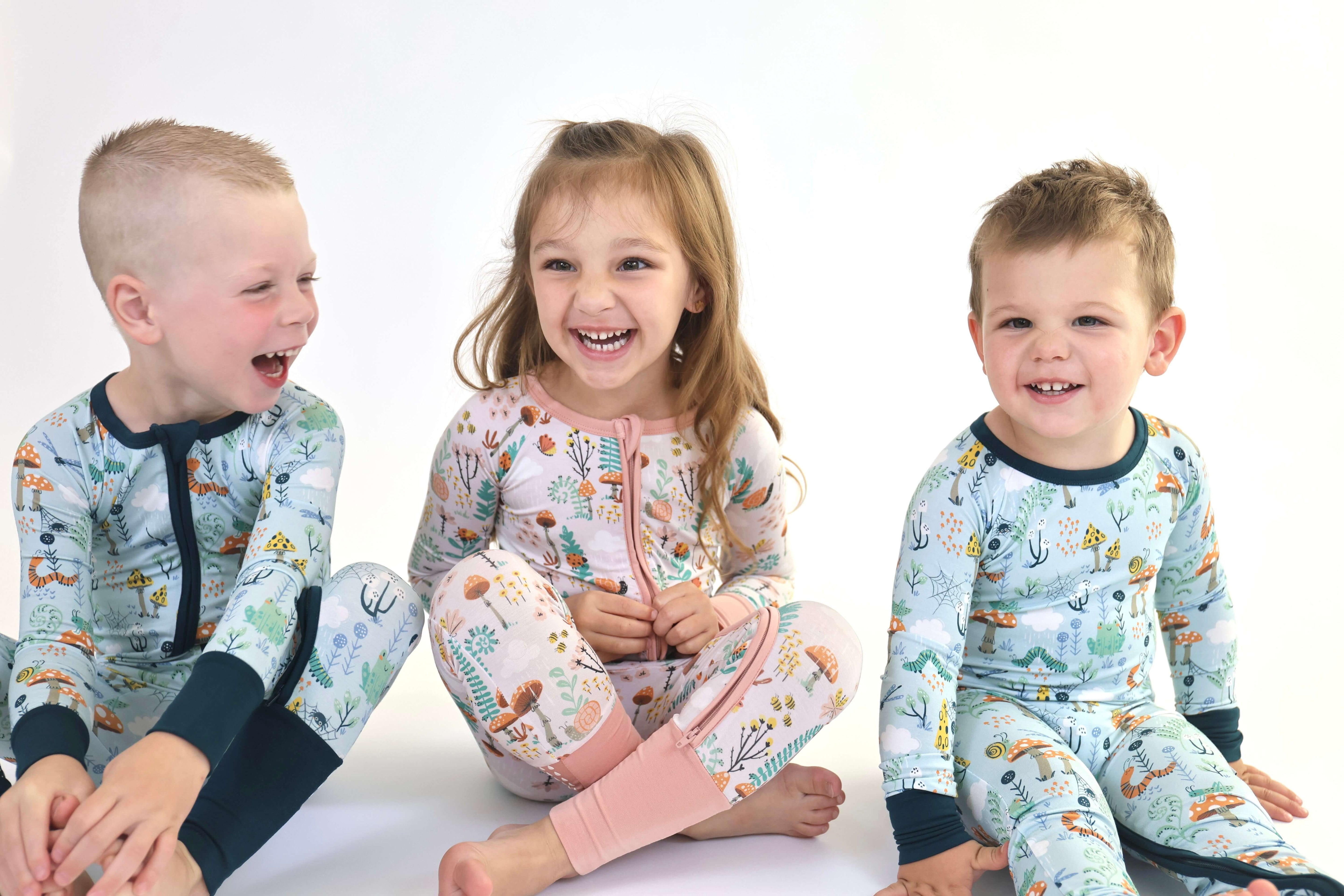 Three cheerful children in colorful pajamas sitting and laughing together.