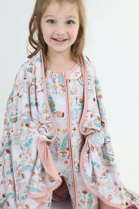 Smiling girl wrapped in a soft bamboo blanket, showcasing the cozy fern design and comfort for snuggles.