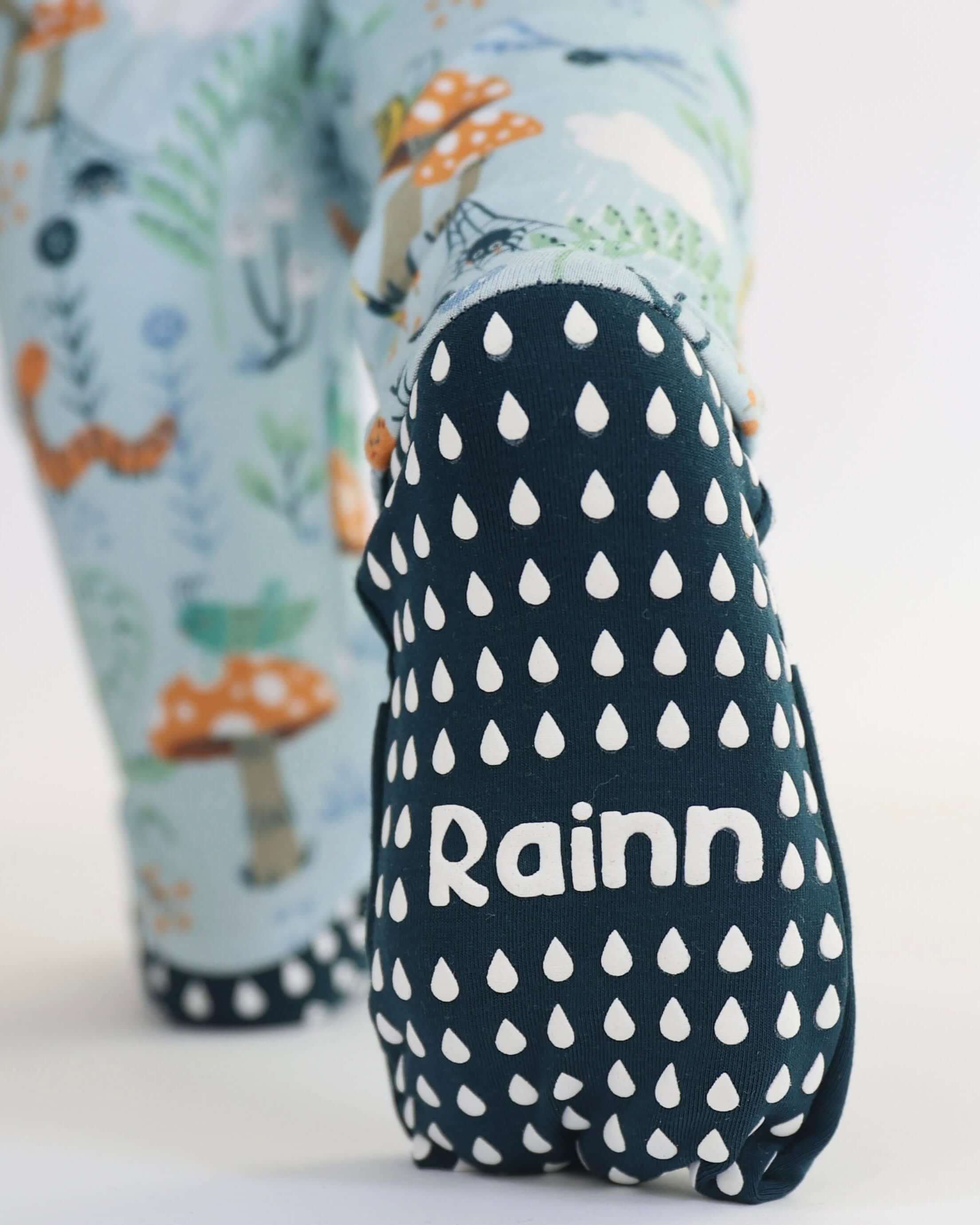 Close-up of baby foot in Bamboo Crescent Zipp Jammies - Critter Hollow with woodland critters and "Rainn" text, focusing on whimsical design.