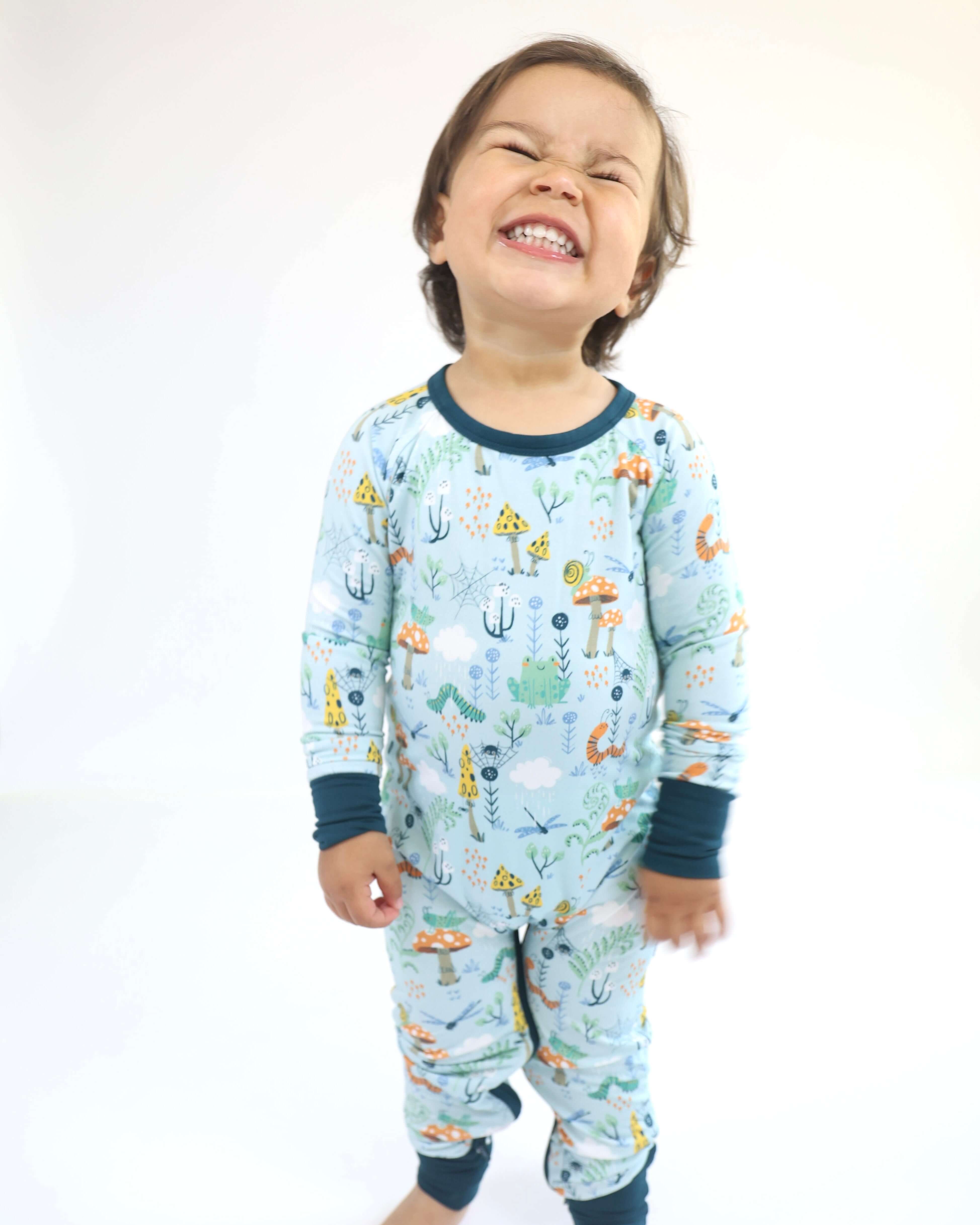 Child smiling in Bamboo Crescent Zipp Jammies with Critter Hollow forest design.