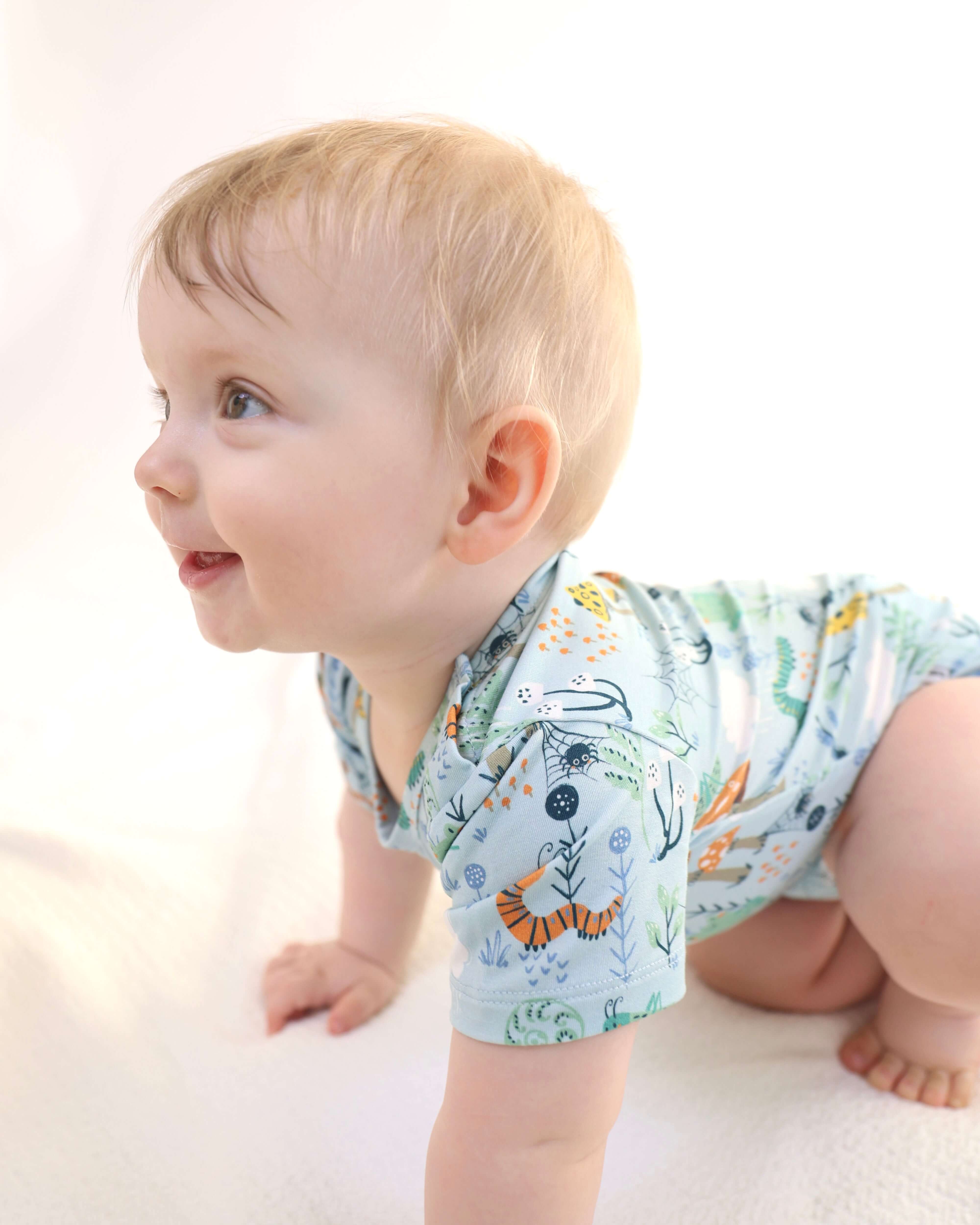 Happy baby crawling in a colorful bamboo onesie featuring playful animal prints.