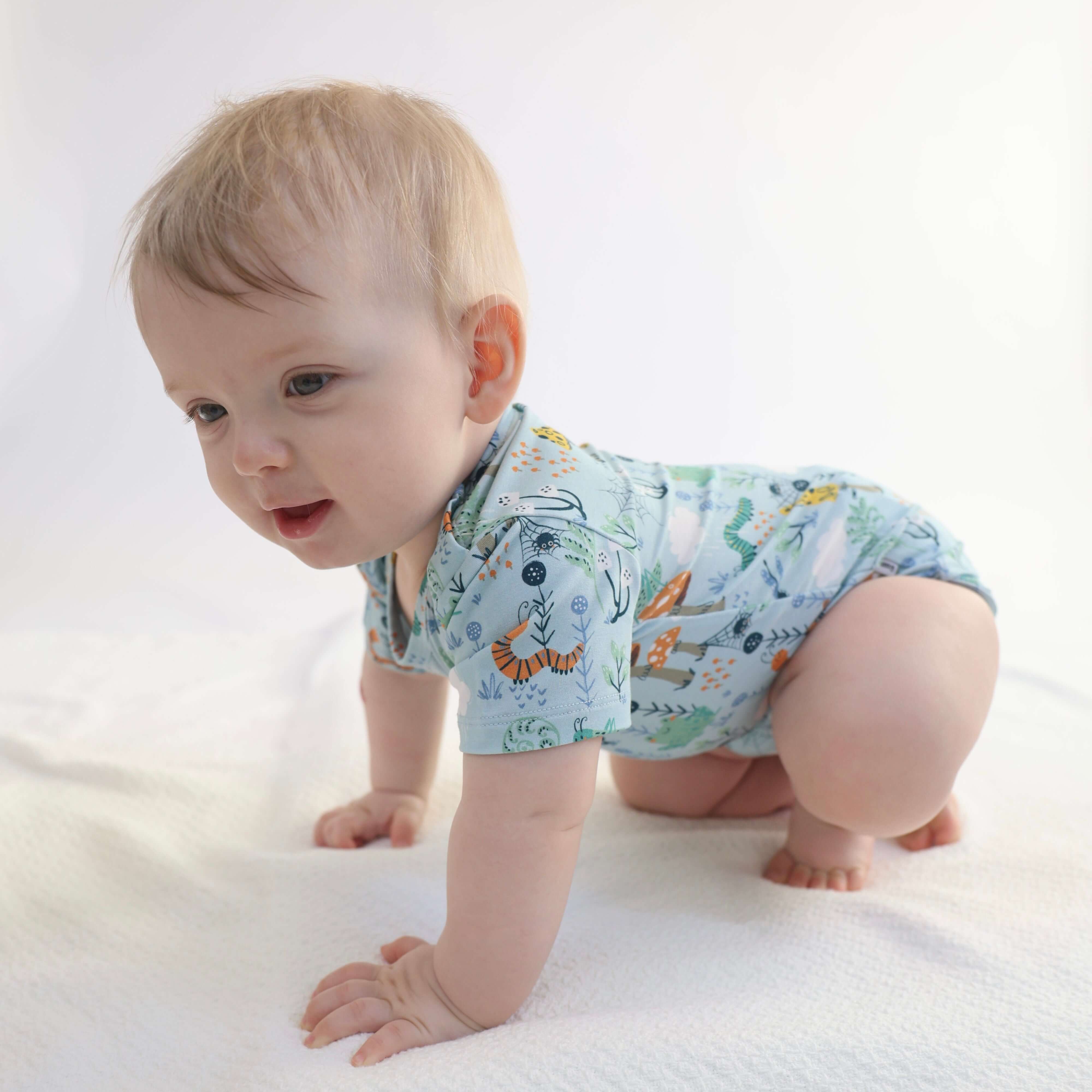 Baby crawling in a soft bamboo onsie with colorful animal prints, showcasing comfort and style.