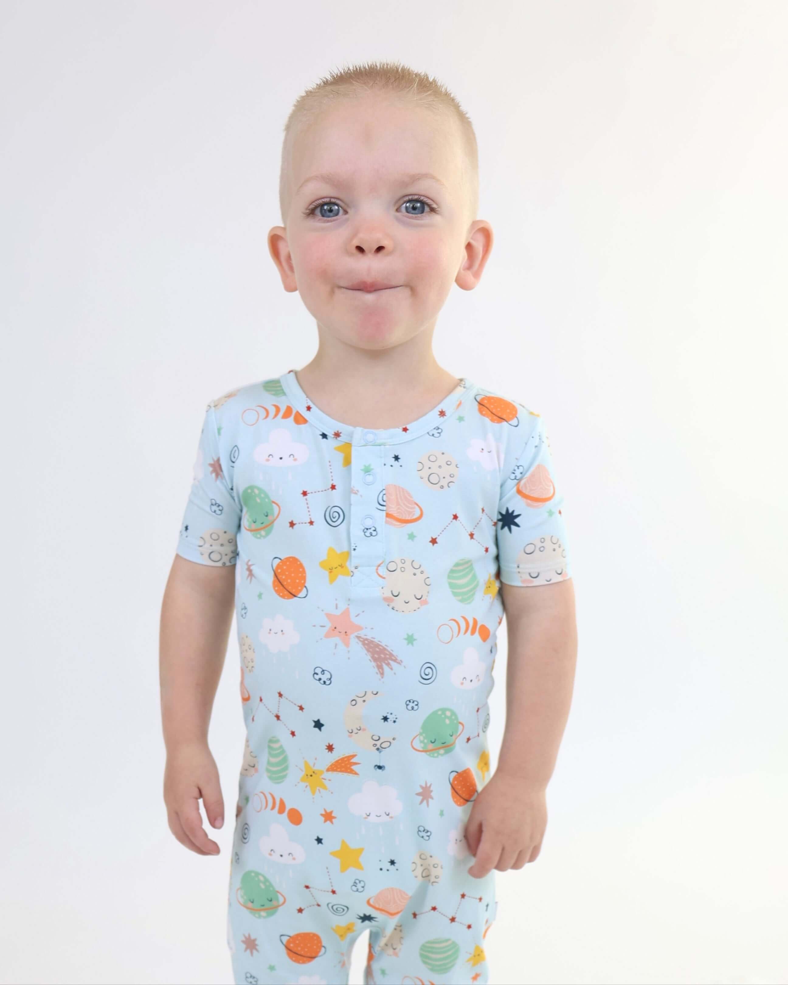 Child wearing Bamboo Pull Up Romper with cosmic print of moons, stars, and planets.
