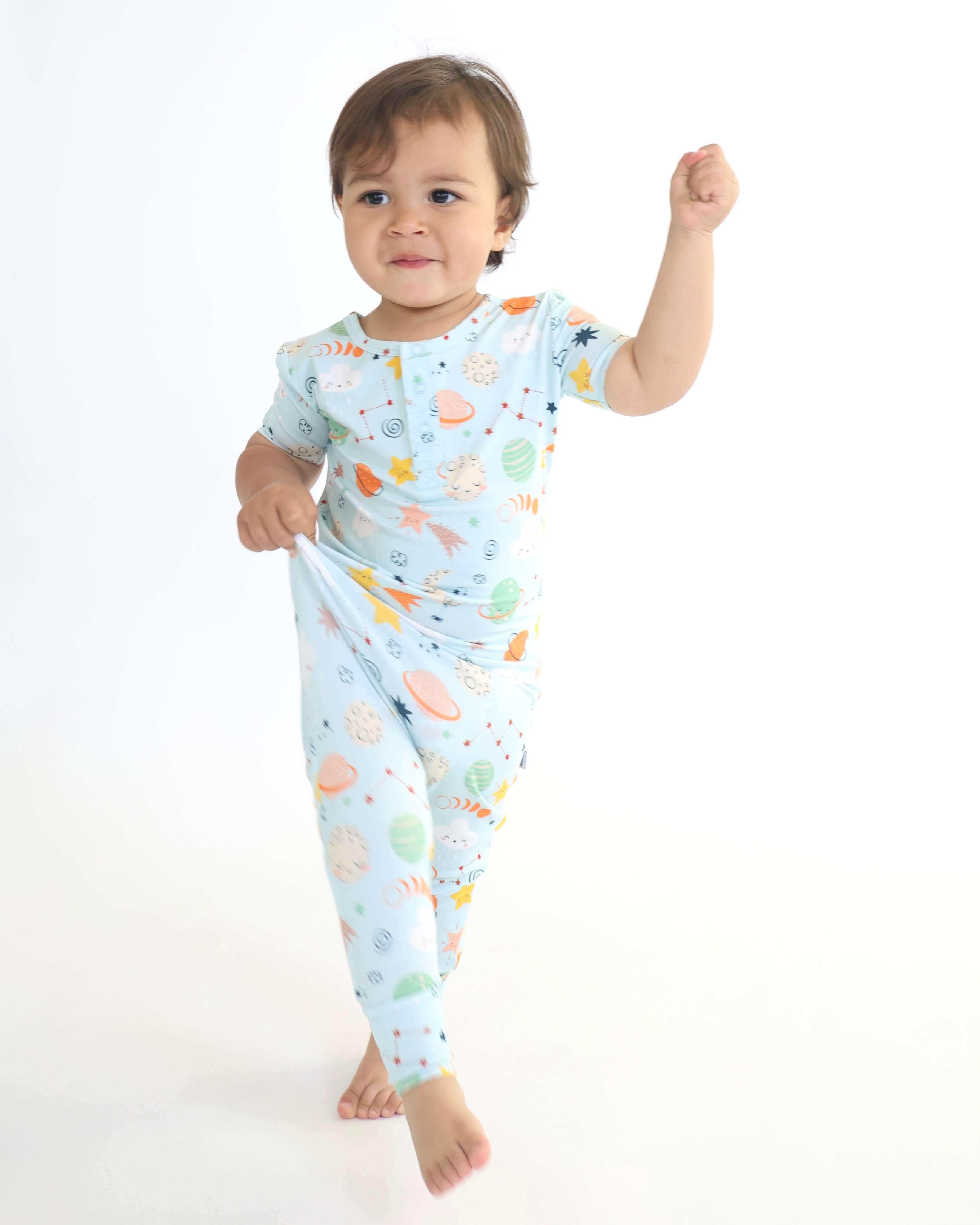 Toddler wearing a colorful Bamboo Pull Up Romper with fun space-themed designs, posing with a cheerful expression.