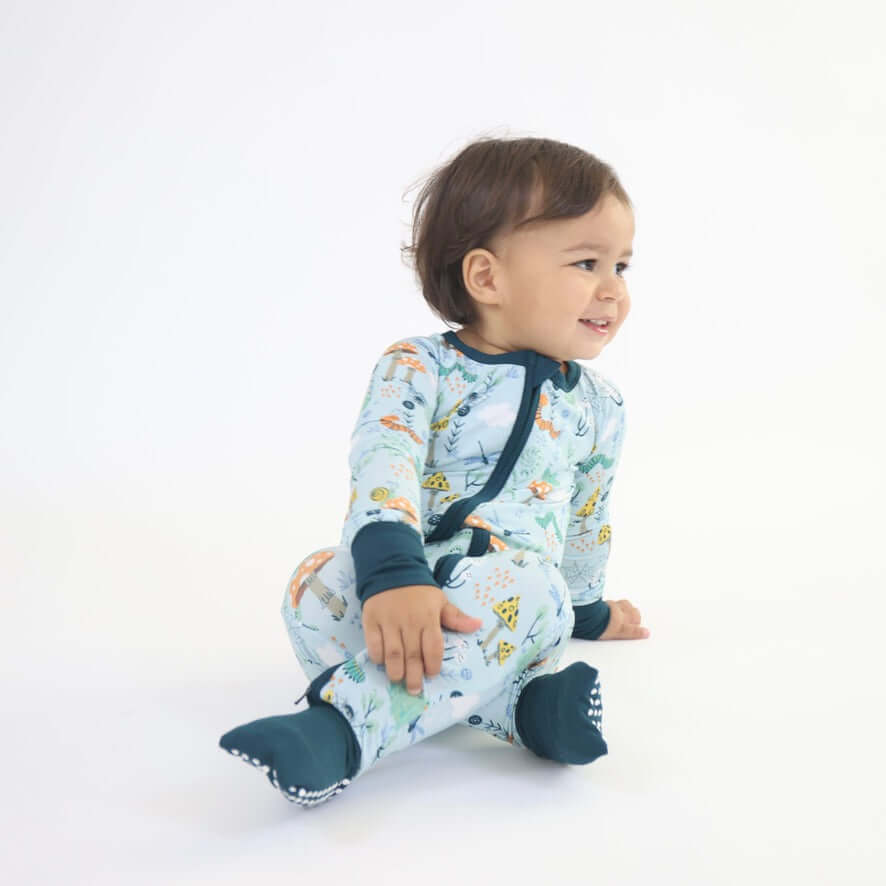 Child wearing Critter Hollow Bamboo Zipp Jammies with nature-inspired print featuring woodland critters like frogs and dragonflies.