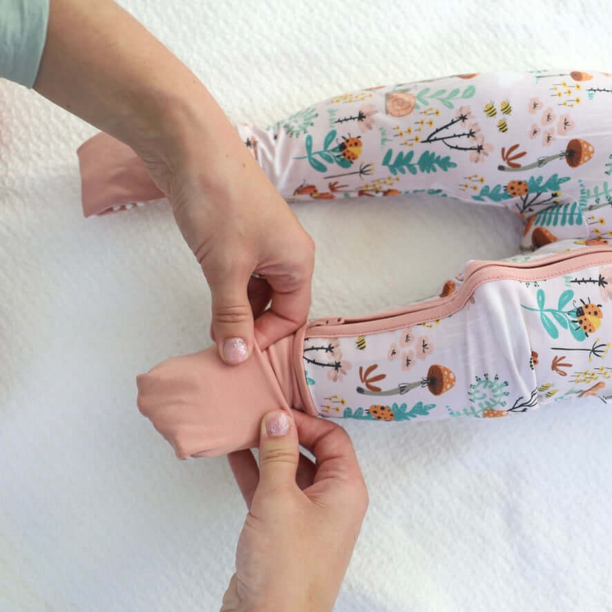 Parent dressing a baby in soft, breathable Bamboo Zipp Jammies with a playful fern print.
