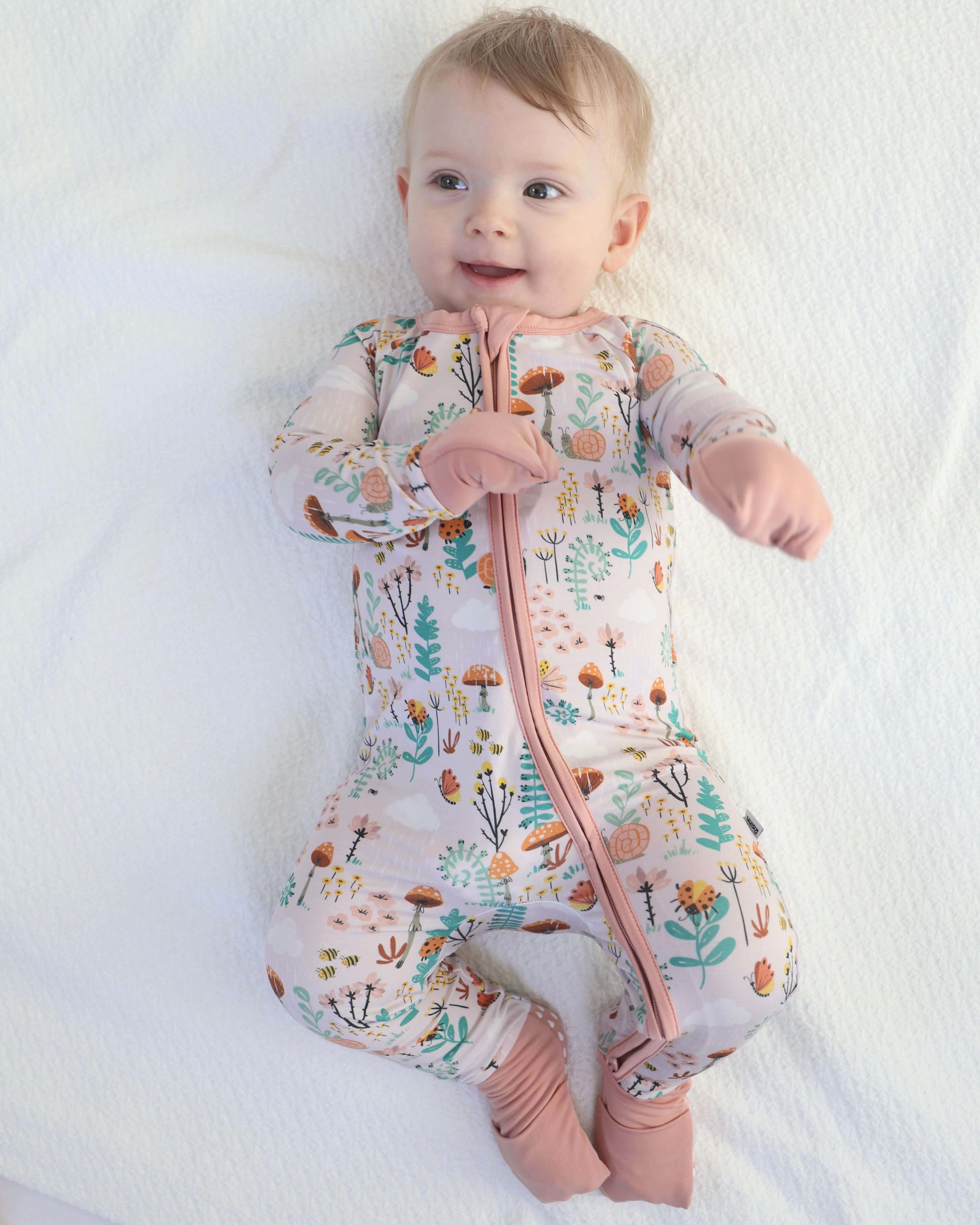 Baby smiling in floral-patterned bamboo Zipp Jammies, perfect for cozy sleep and playful moments.