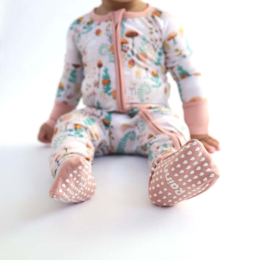 Baby in floral bamboo Zipp Jammies with pink accents and non-slip soles, perfect for comfy sleep.