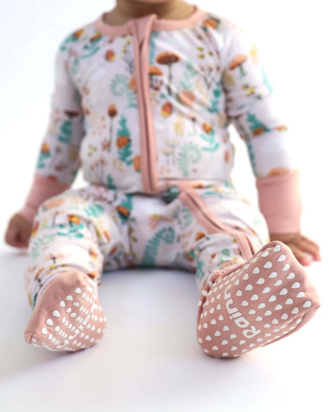 Baby in floral bamboo Zipp Jammies with pink accents and non-slip soles, perfect for comfy sleep.