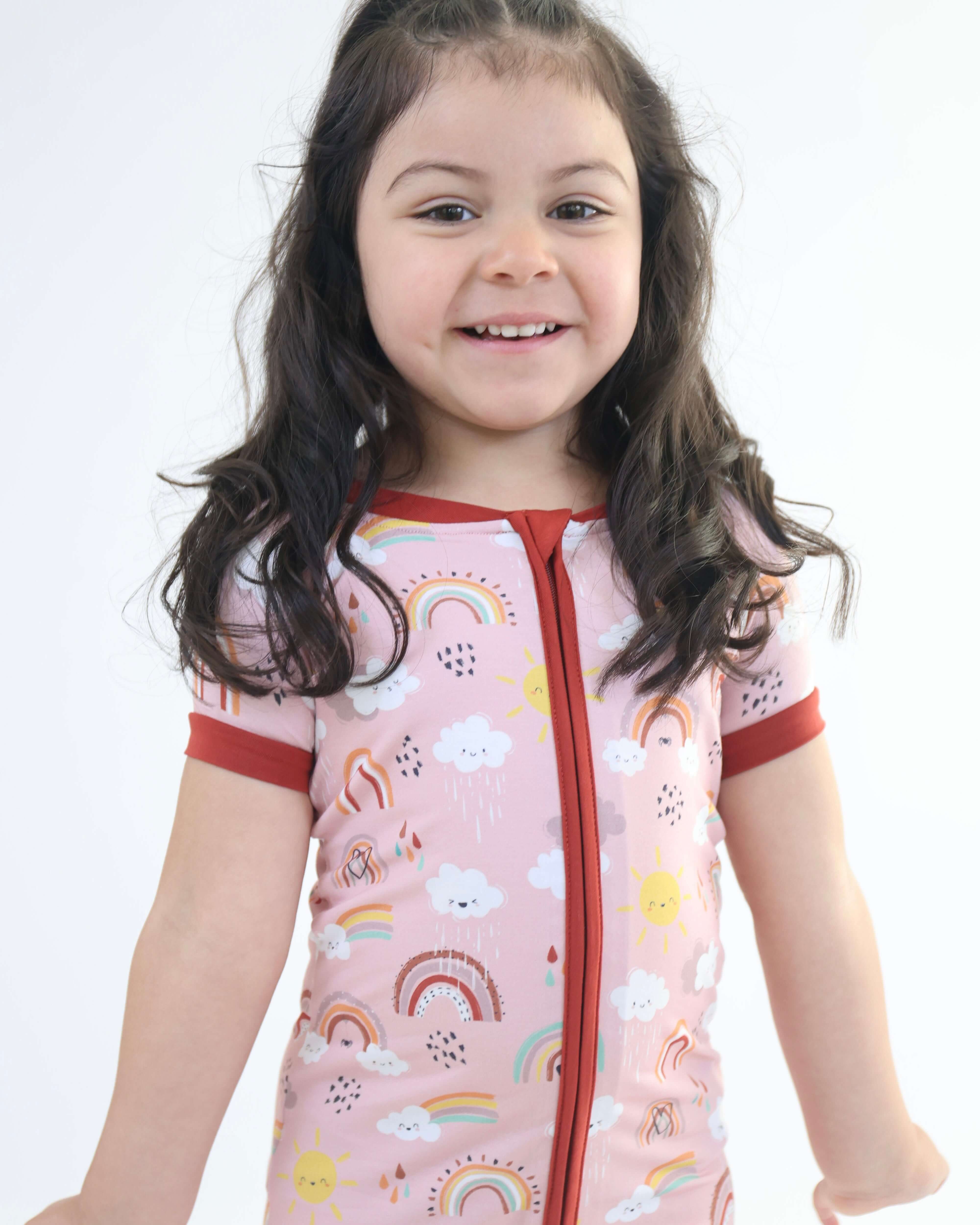 Smiling child in a Rainnbow Short Zipp Romper with playful rainbow print, perfect for cozy and colorful days.