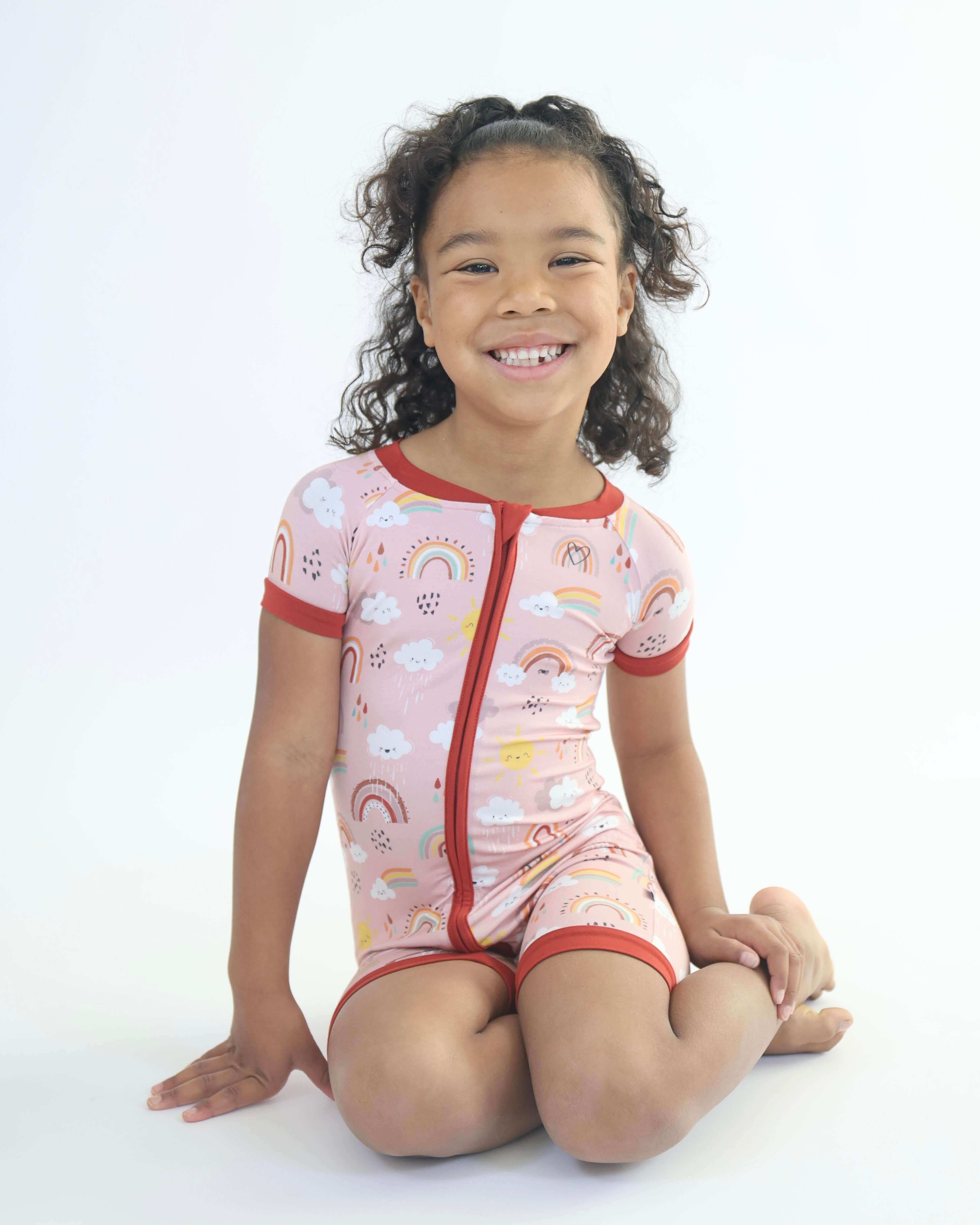 Child wearing Bamboo Short Romper with nature-inspired rainbow print, perfect for playful adventures.