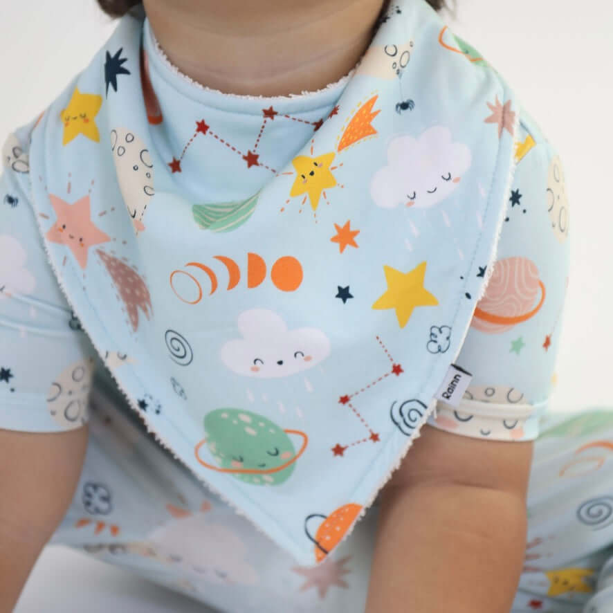 Bamboo bandana bib featuring a cosmic design with stars, planets, and clouds, perfect for drooling babies.