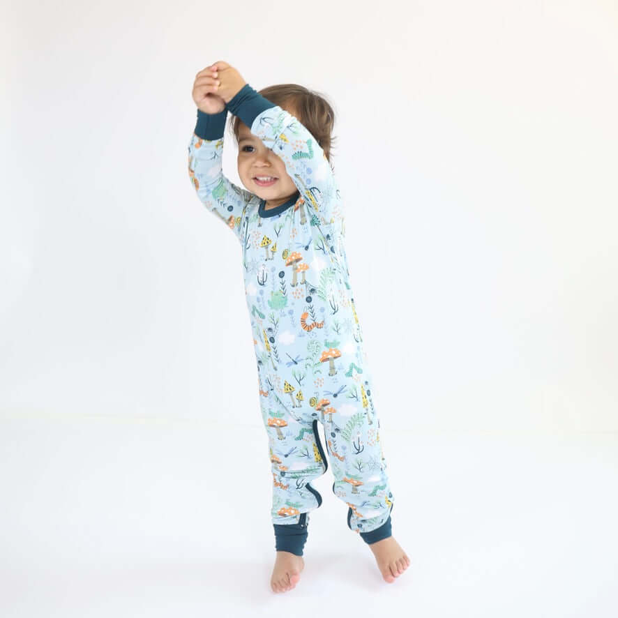 Toddler in colorful Bamboo Crescent Zipp Jammies, playfully raising arms, showcasing cozy and breathable design.