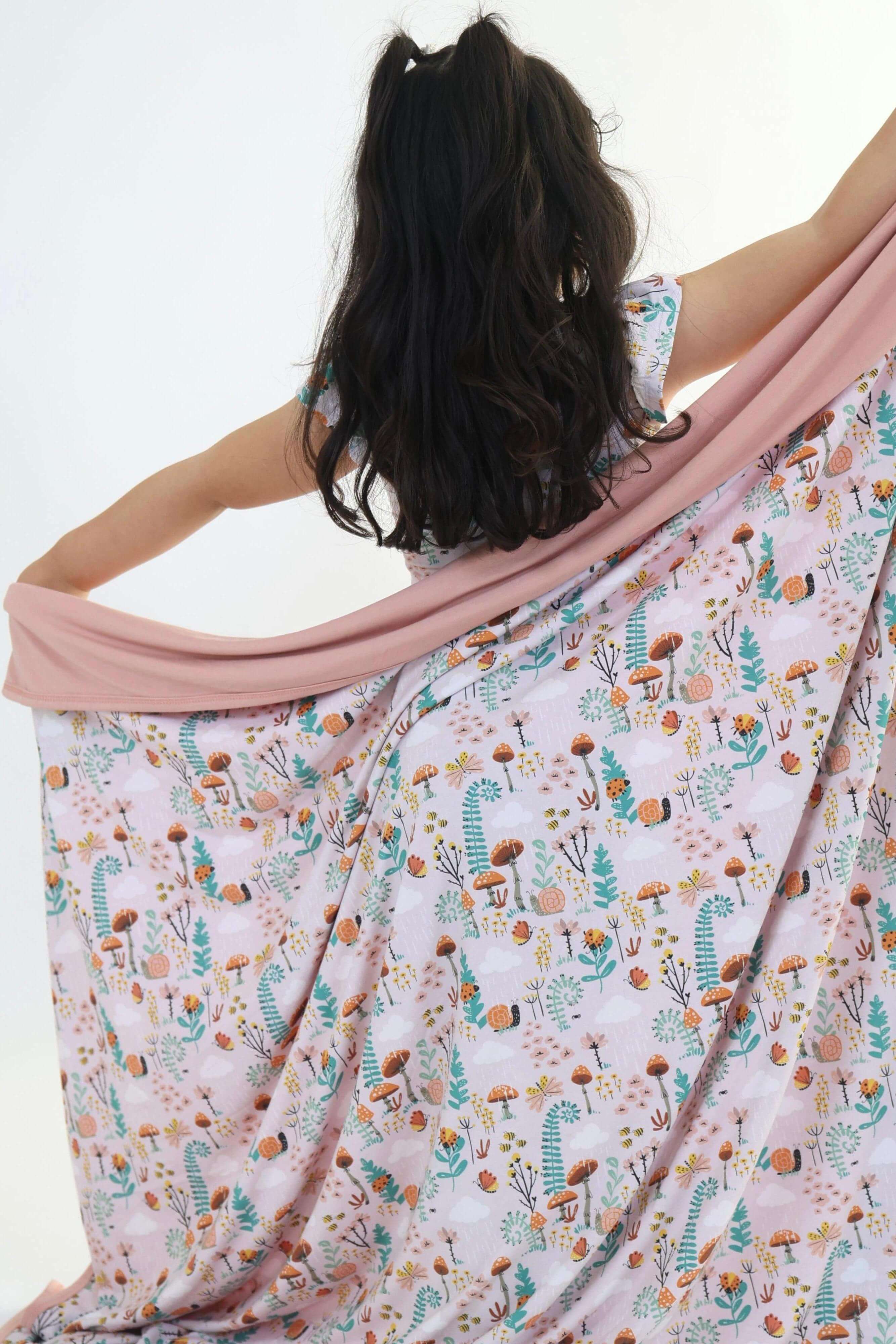 Child wearing a cozy bamboo blanket with a colorful fern pattern, showcasing its soft and breathable fabric.