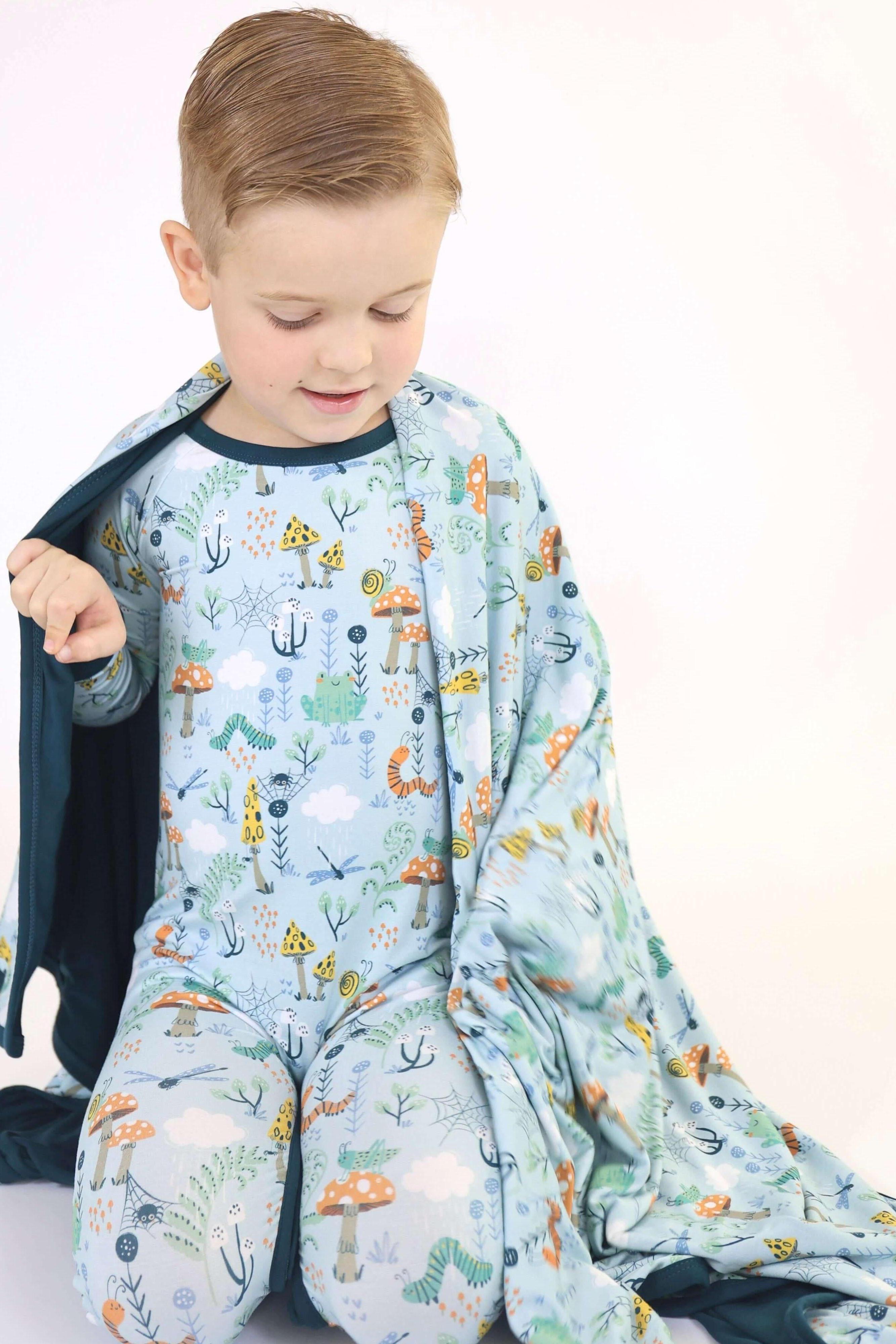 Cozy child in RainnWeave™ blanket and pajamas, featuring nature-inspired prints in earthy colors.