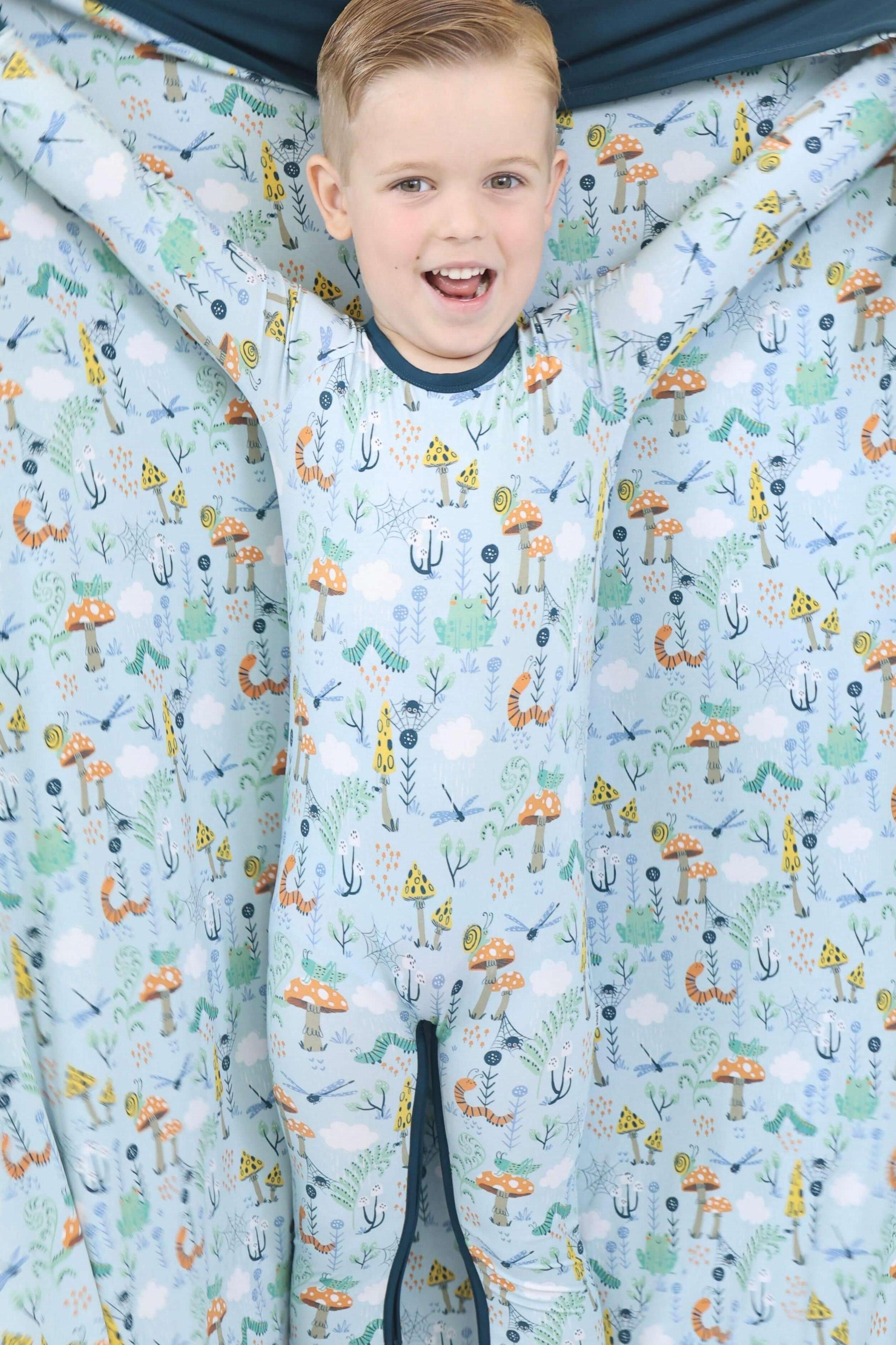 Happy child in Critter Hollow Rainn Cozy Blanket, showcasing vibrant eco-friendly prints and a snug fit.