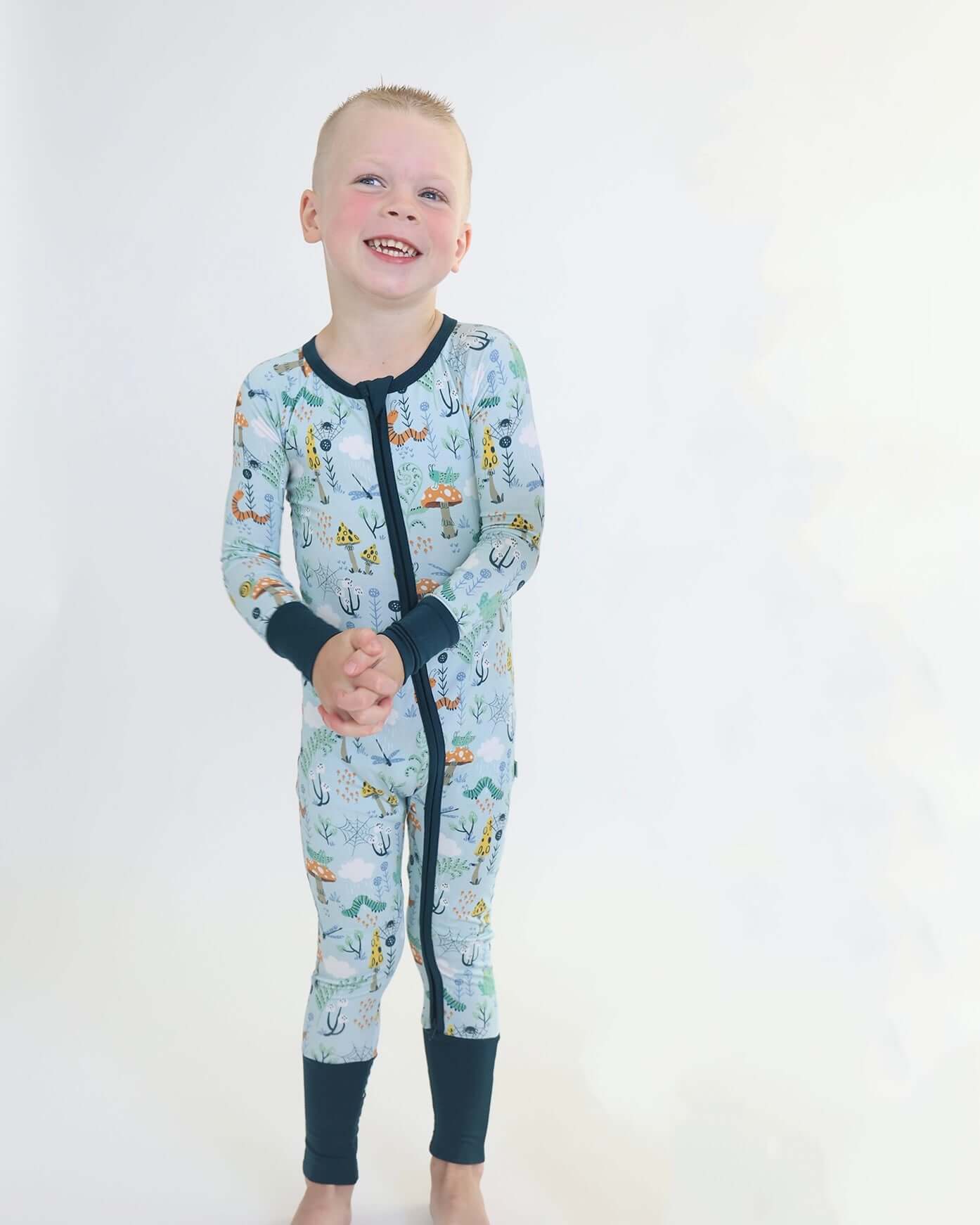 Happy child in Critter Hollow Zipp Jammies with RainnWeave™ bamboo, featuring nature-inspired prints and comfy design.