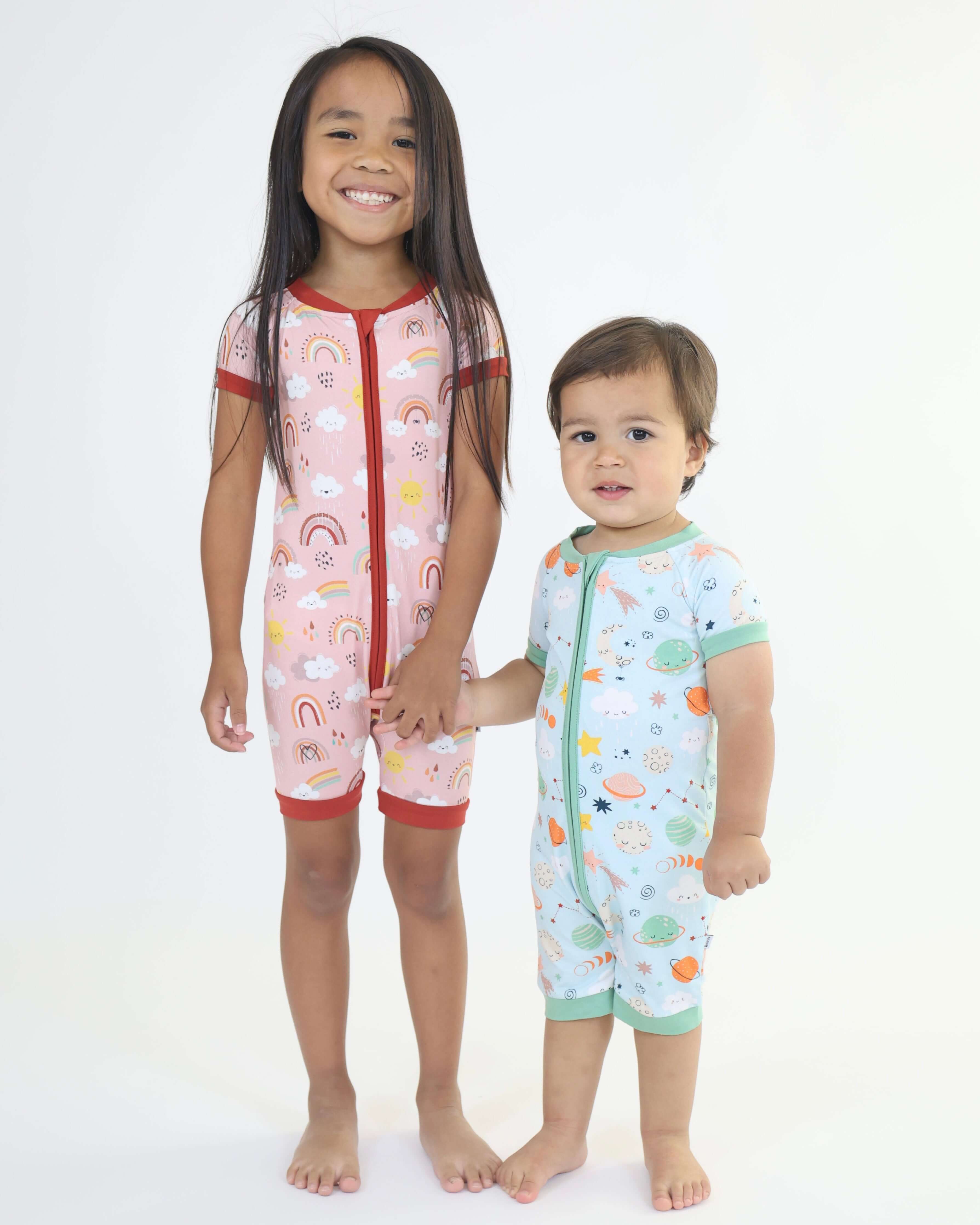 Two kids smiling in colorful Rainnbow Short Zipp Rompers with playful patterns, perfect for cozy comfort and fun.