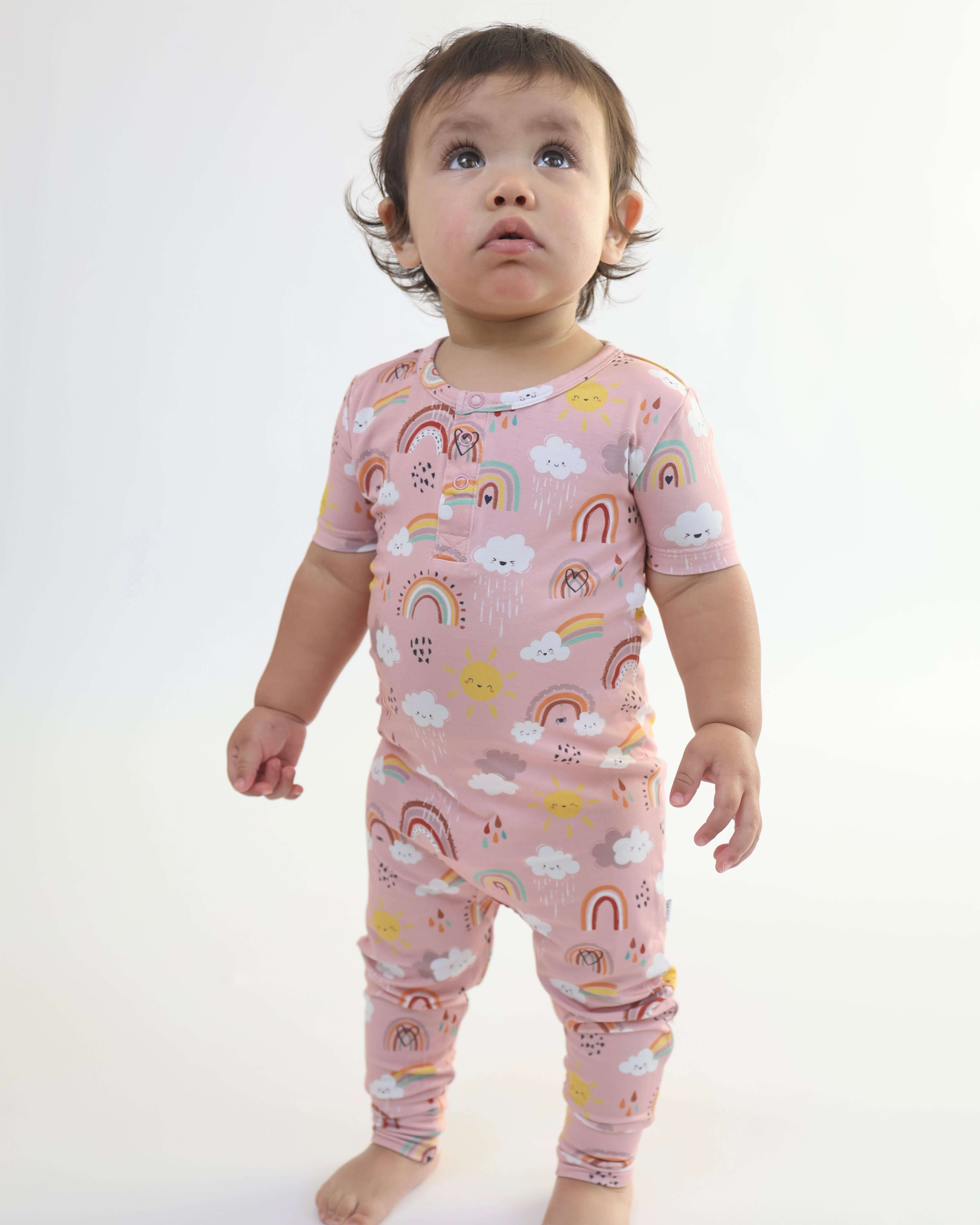 Baby wearing Rainnbow pull-up romper in pastel colors, featuring rainbows and clouds, perfect for cozy diaper changes.
