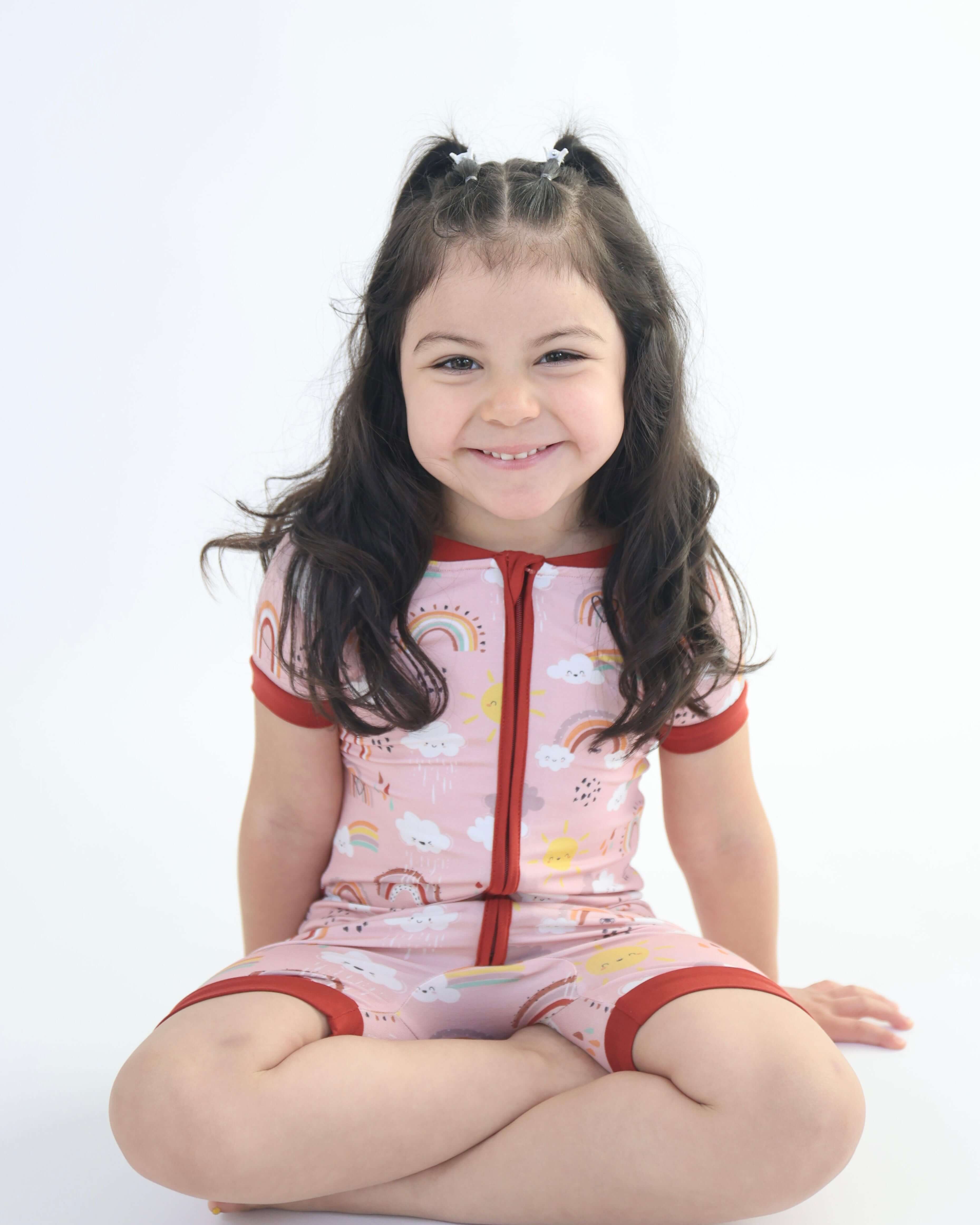Smiling child in Rainnbow short zipp romper with fun prints, displaying soft, breathable, eco-friendly fabric.