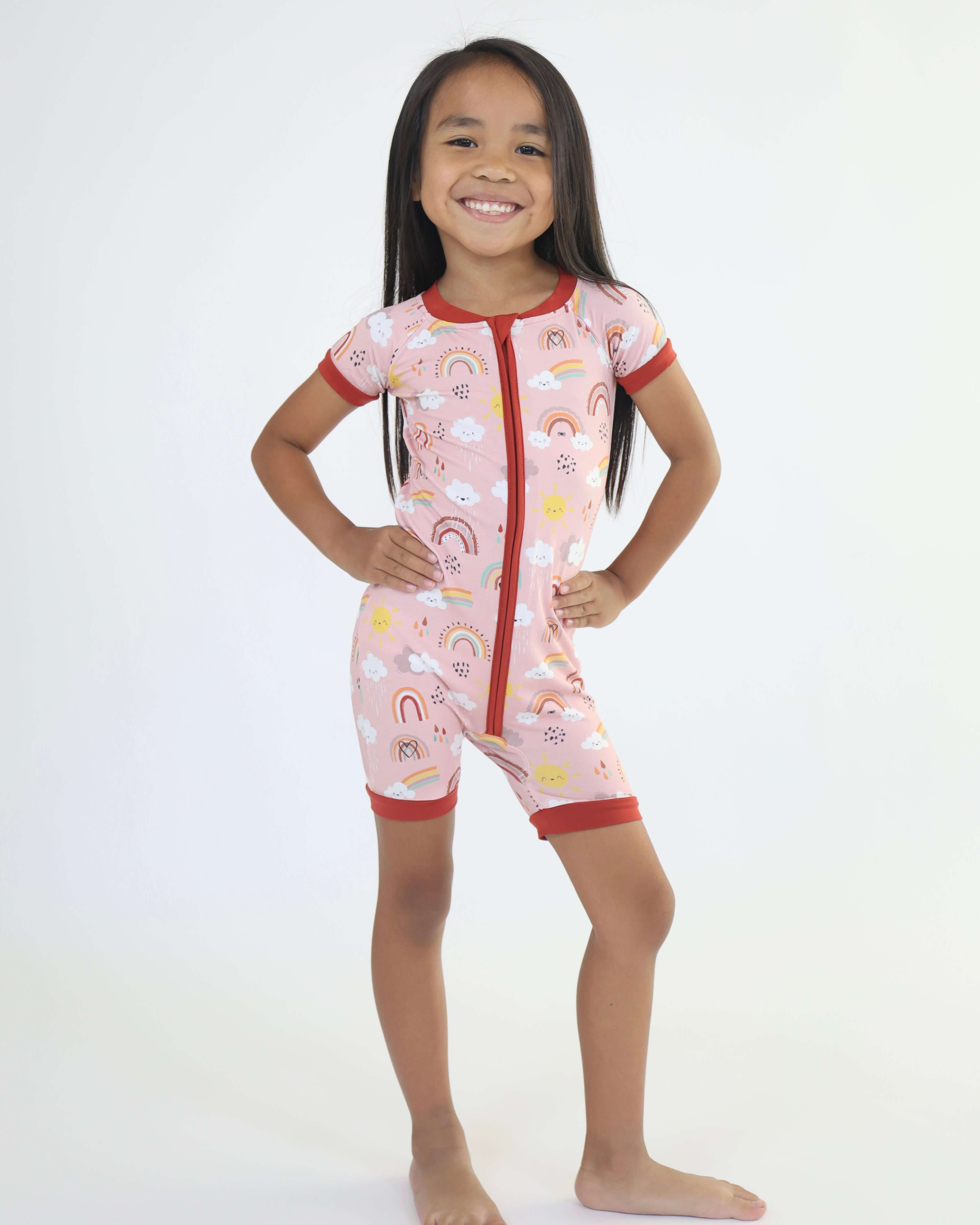 Smiling child in Rainnbow short zipp romper, featuring colorful prints and breathable bamboo fabric.